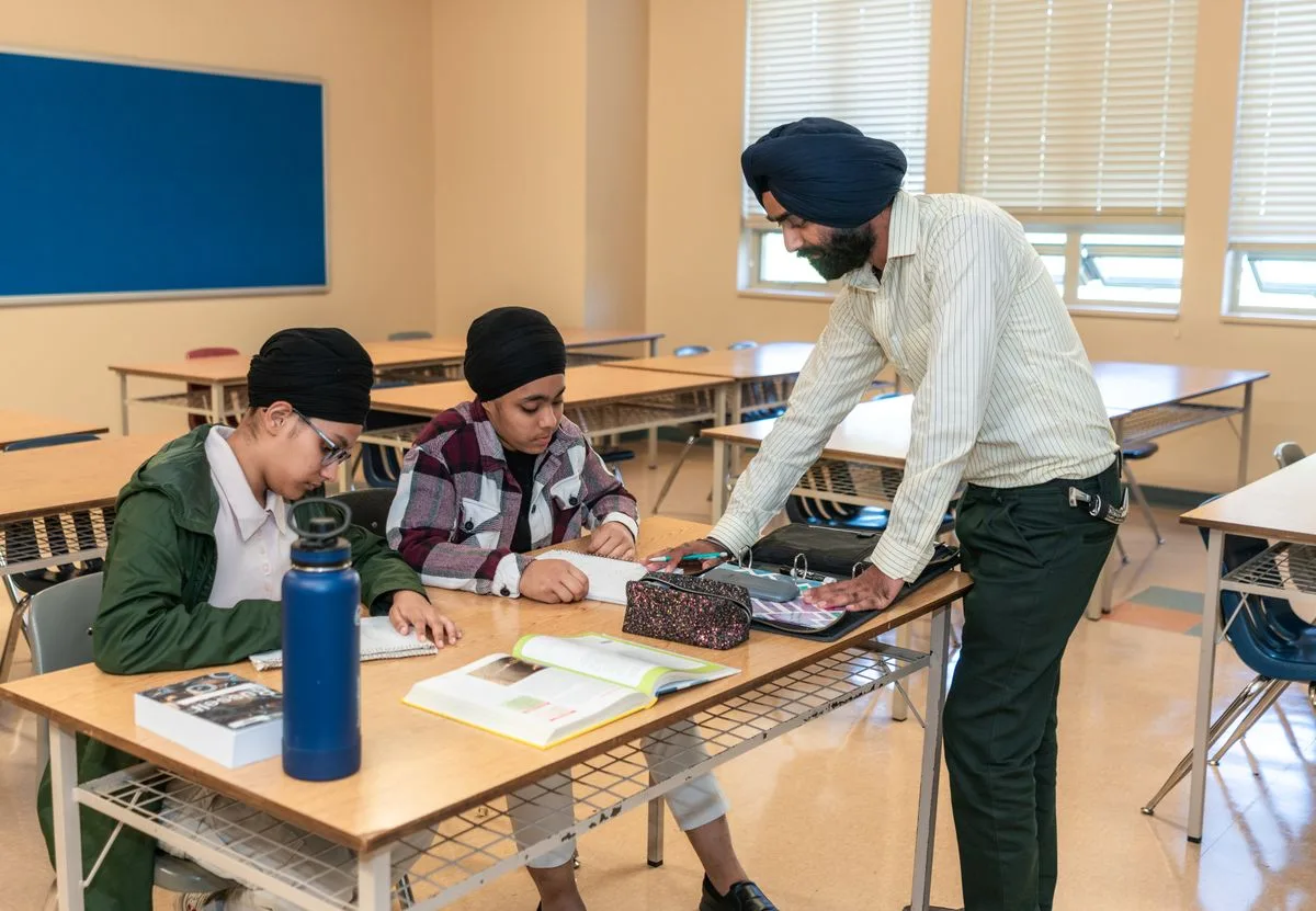 Indian teacher helping two students in a classroom