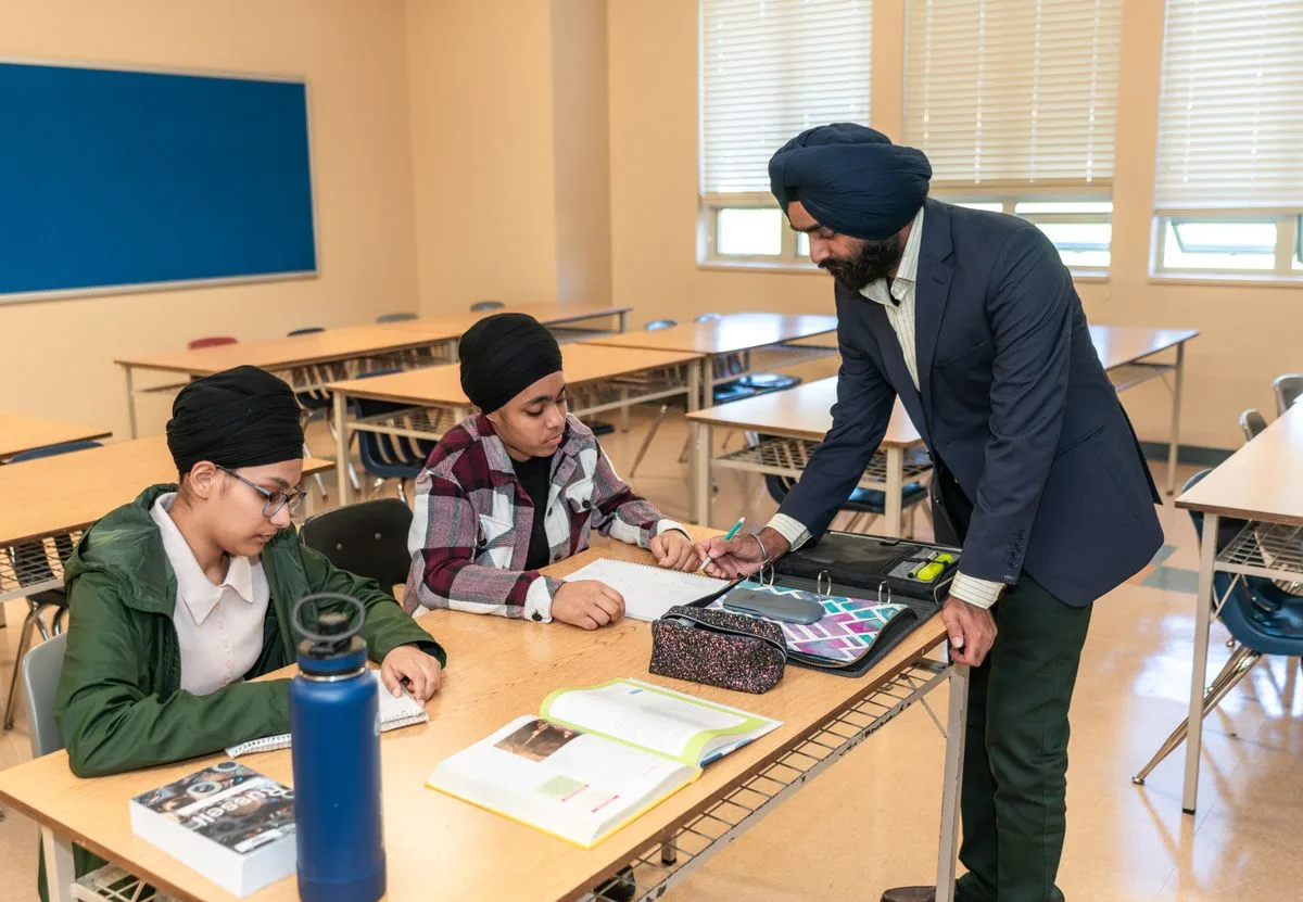 Indian teacher assisting two students in a classroom