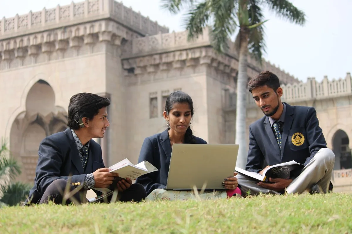 Indian college students in blazers sharing a laptop on campus