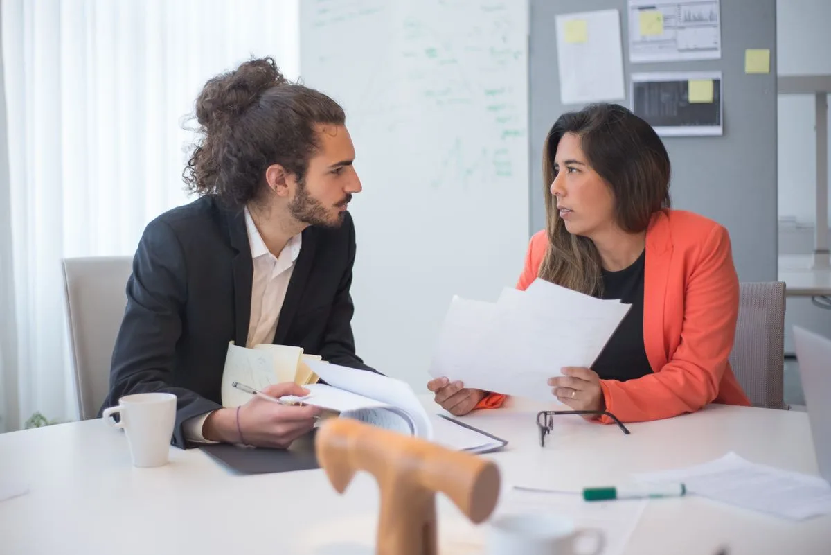 Indian professionals discussing documents at an office desk